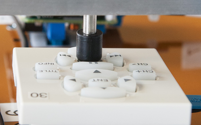 Plunger pressing a button on an Extron button panel